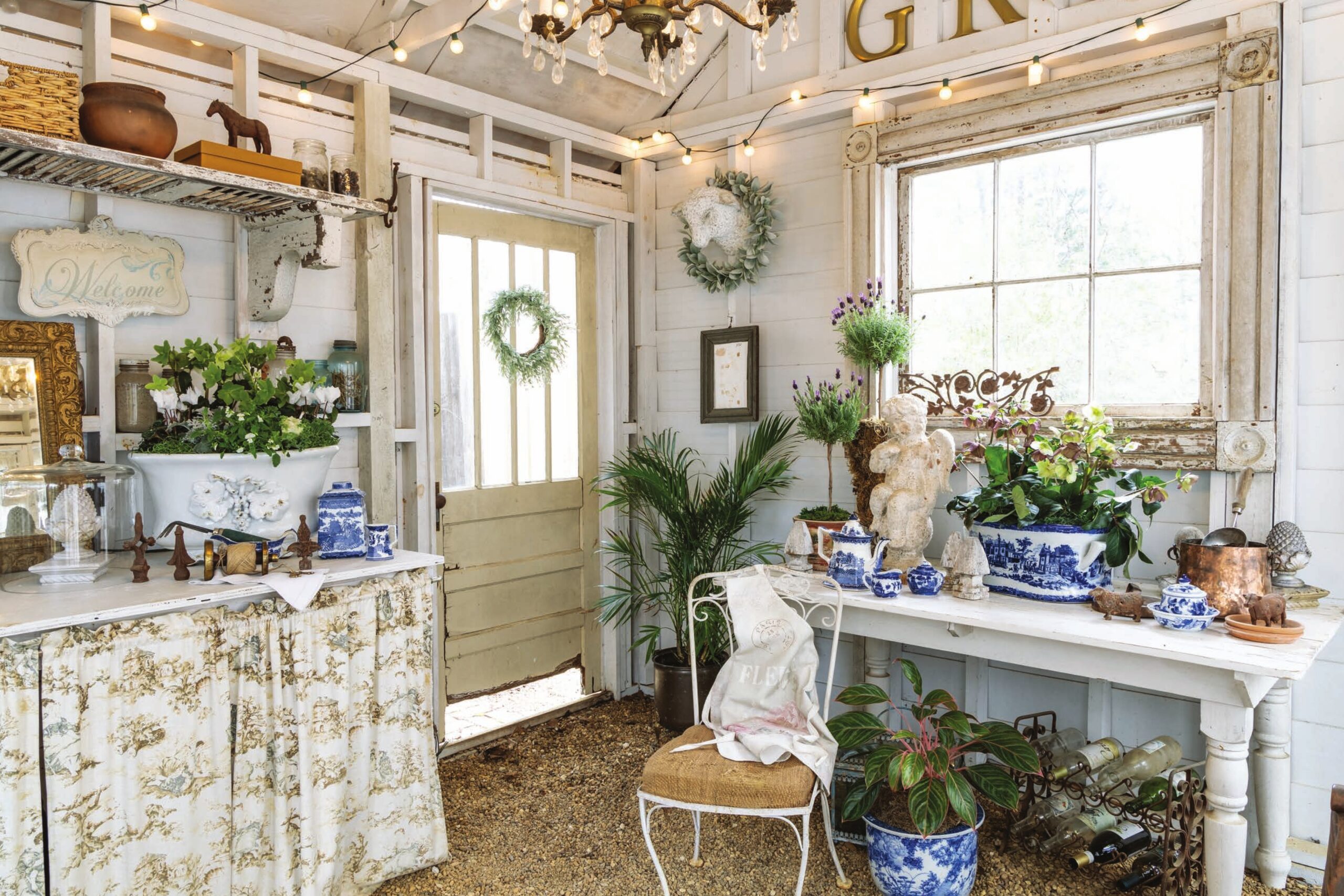 A garden shed furnished with blue-and-white accessories, greenery, and cozy textiles.