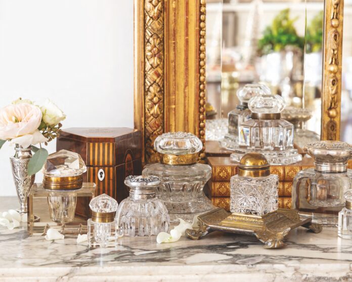 A collection of inkwells arranged in front of a mirror.