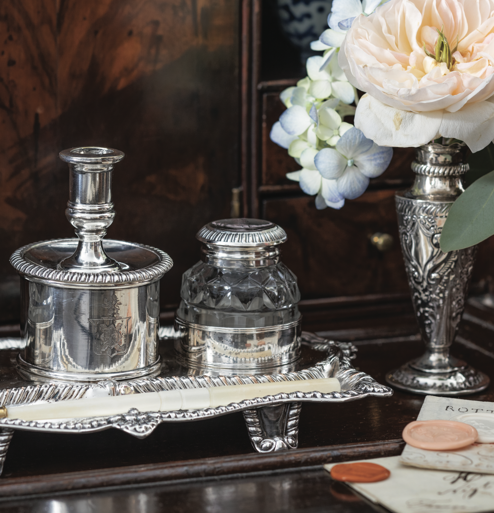 2 inkwells near a vase of flowers.