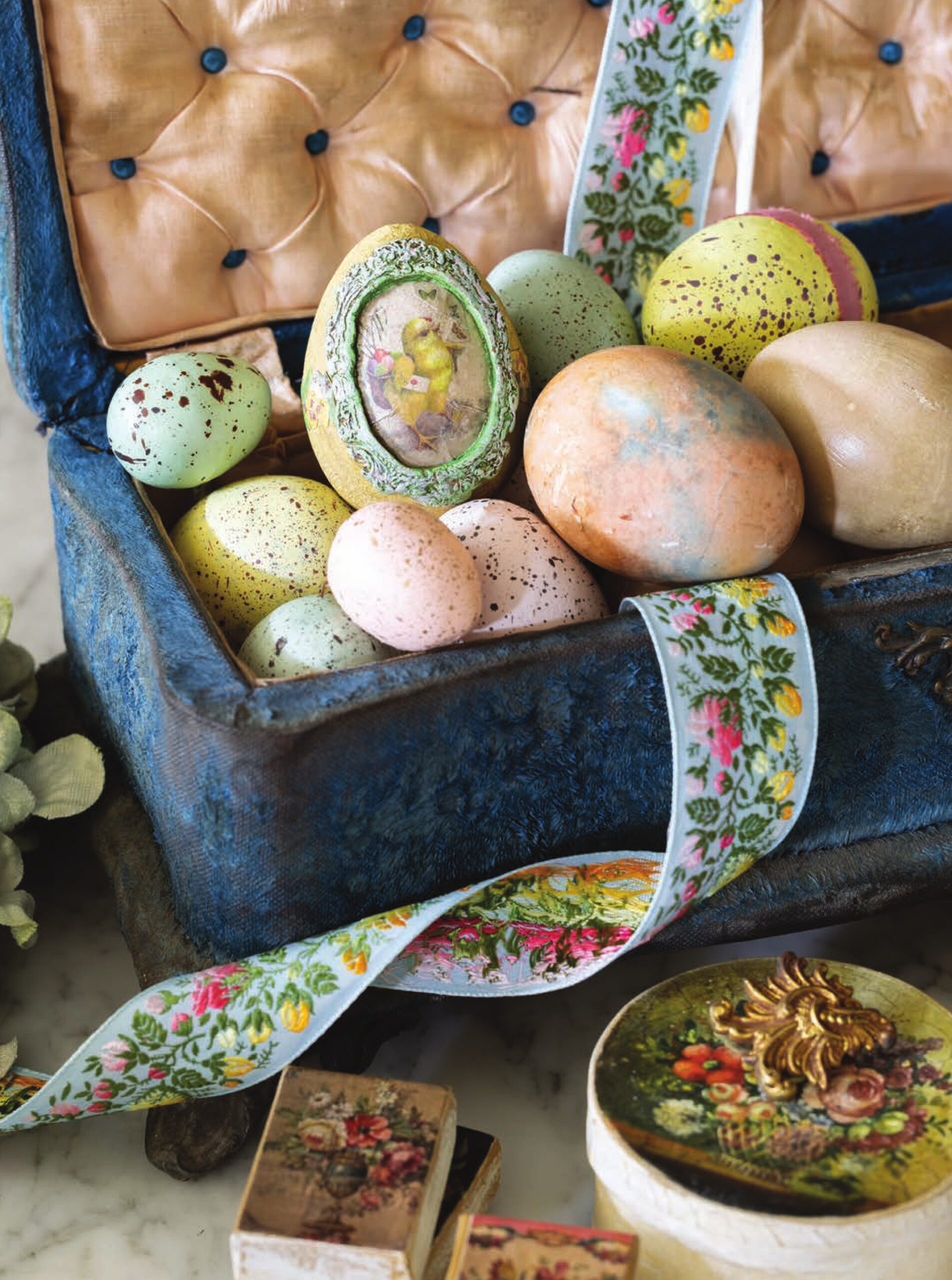 Pastel colored easter eggs with speckles of color nestled in a box with floral ribbon.