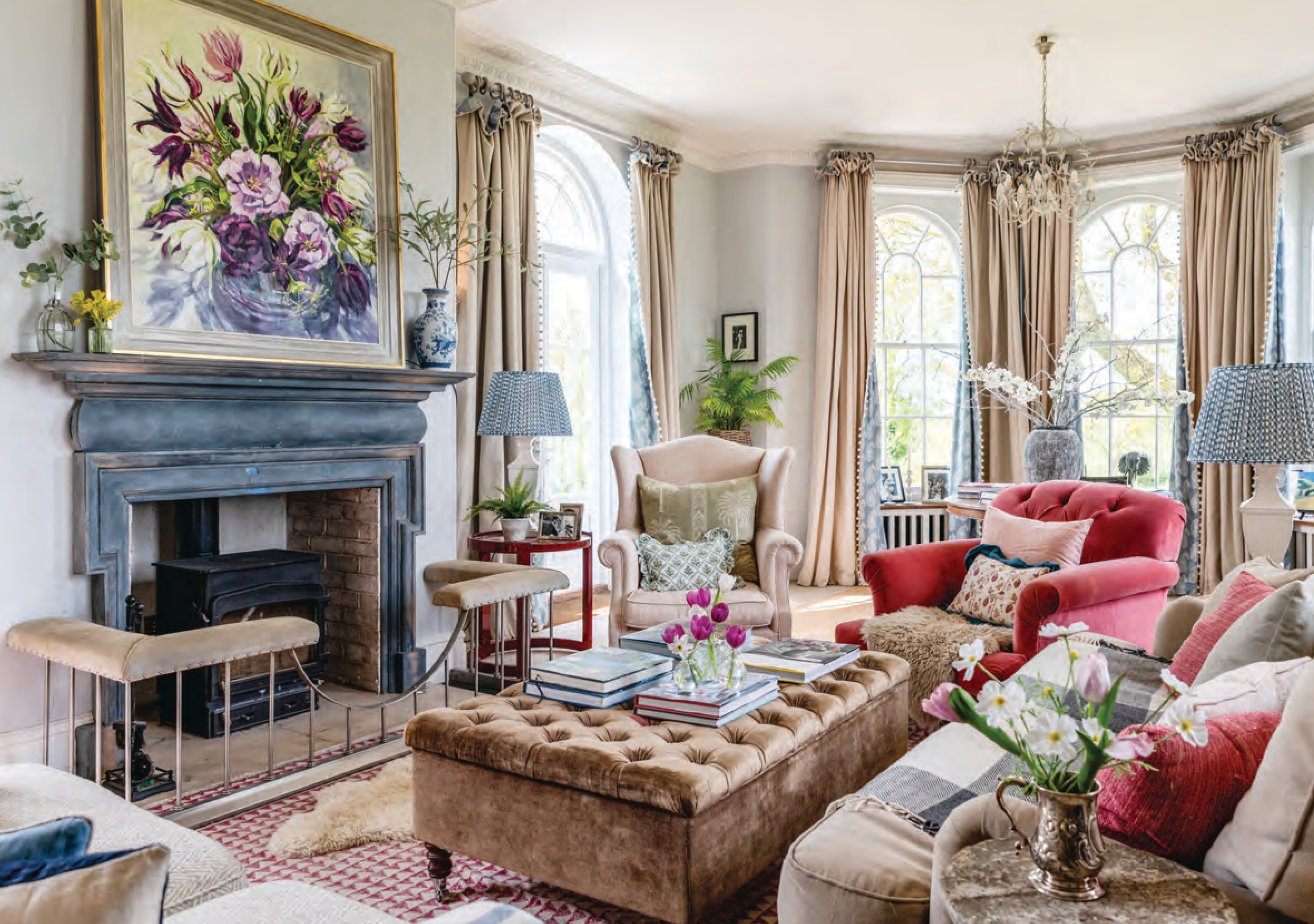 An English-Country style living room, with a fireplace, cozy armchairs, and big windows.
