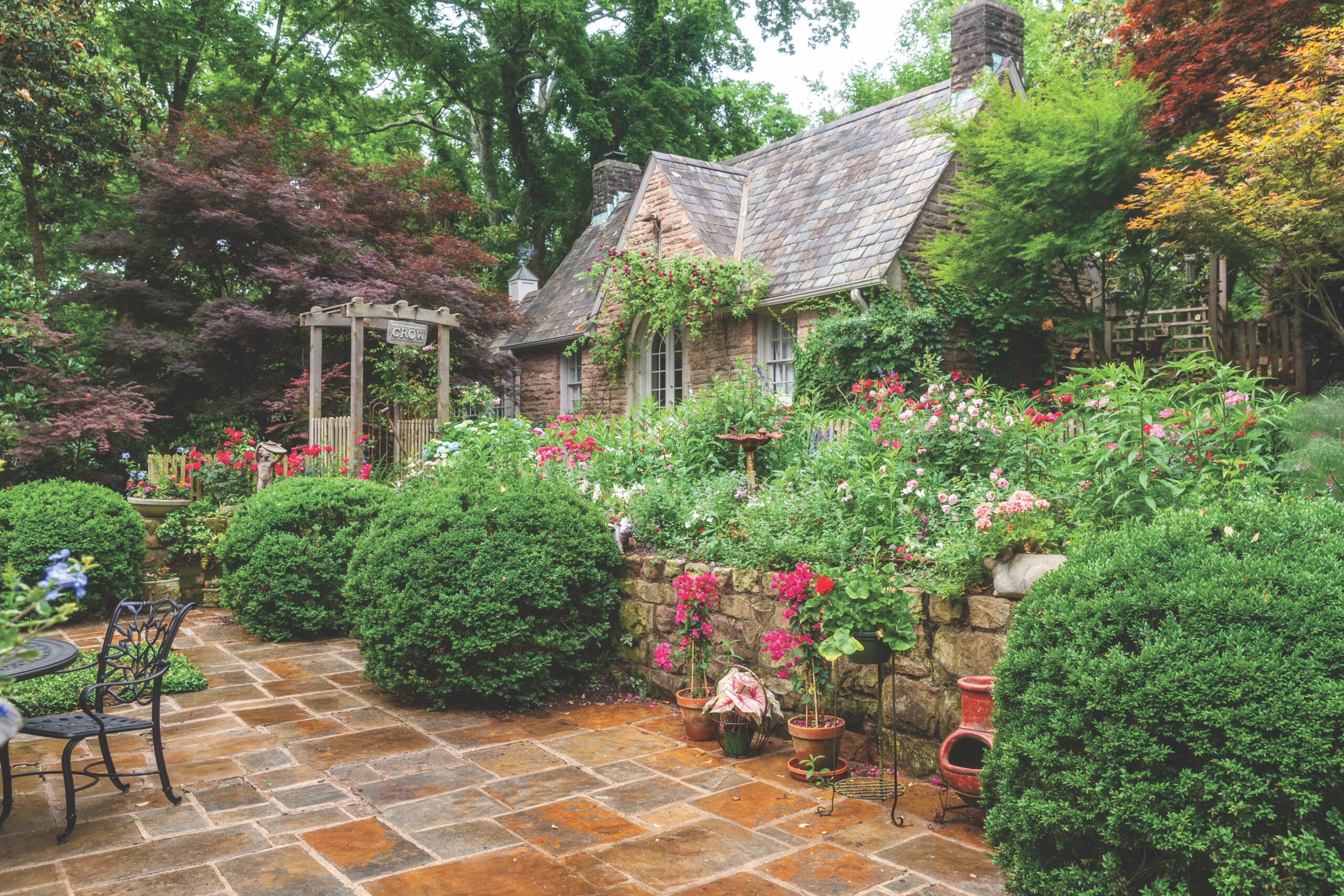 A bountiful spring garden and a cottage with a patio.