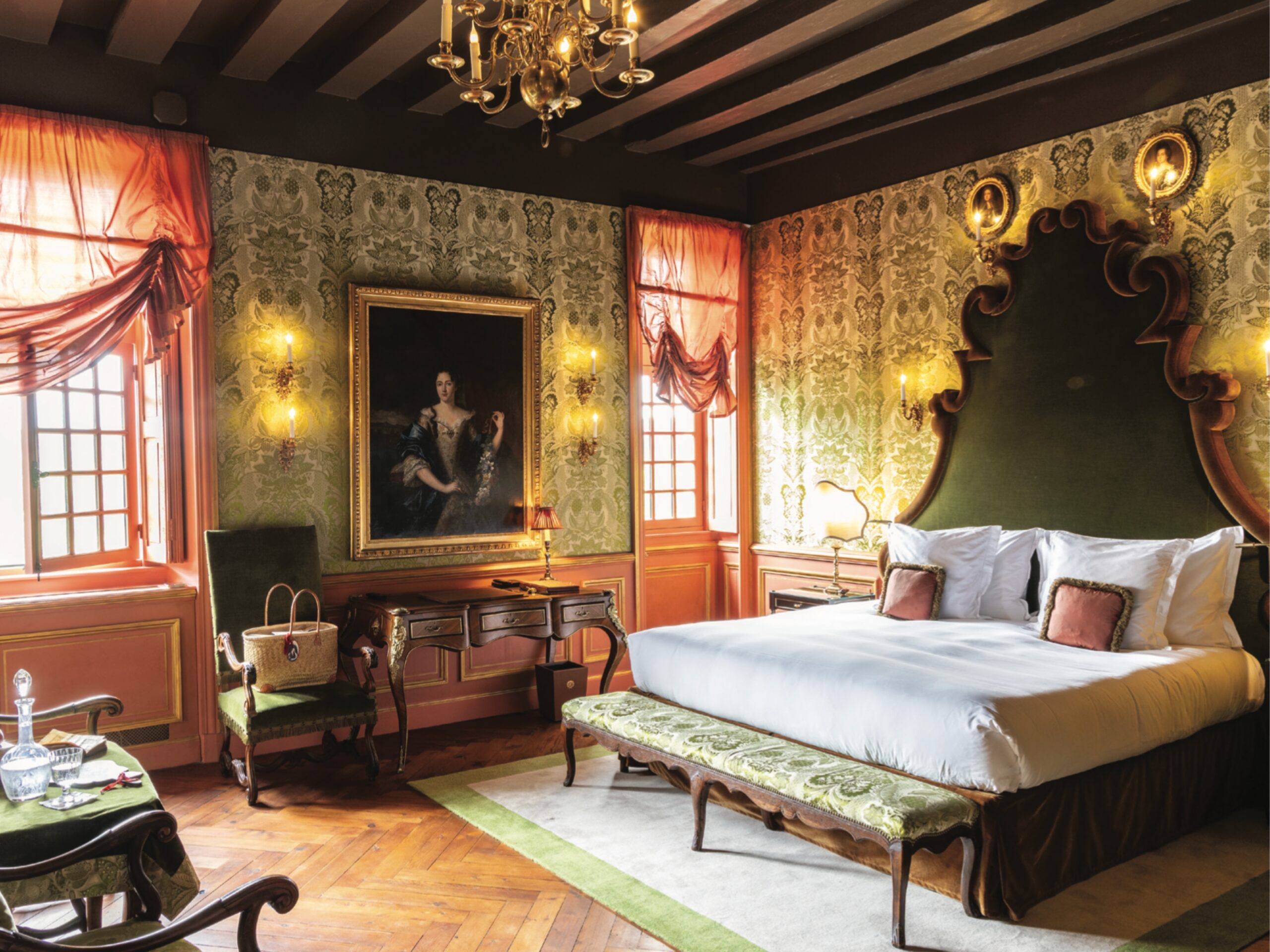 An opulent bedroom at Château Louise de La Vallière, with wallpaper, an ornate bed, an oil portrait, and peach accents.