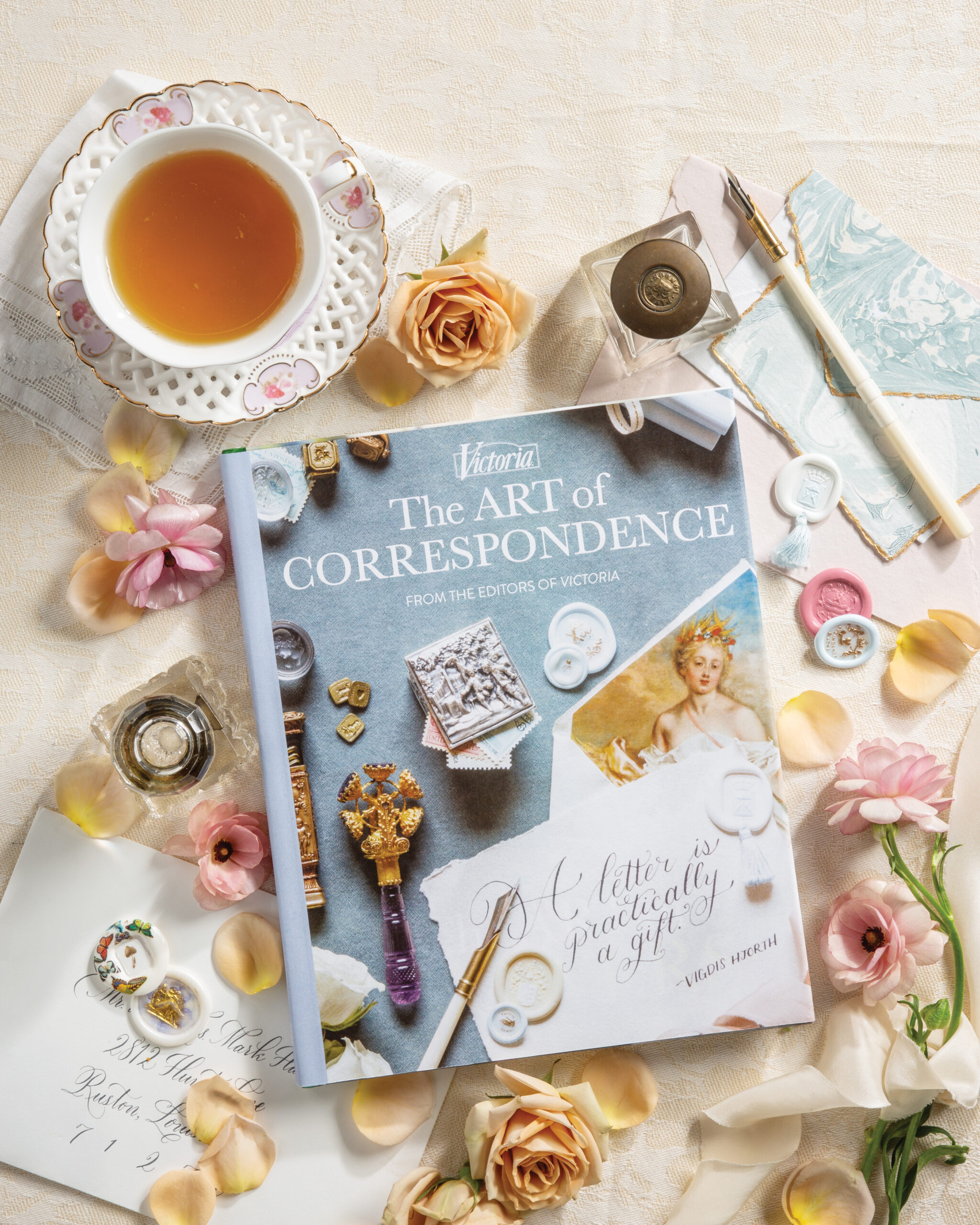 Art of Correspondence book with letter writing accessories and a cup of tea