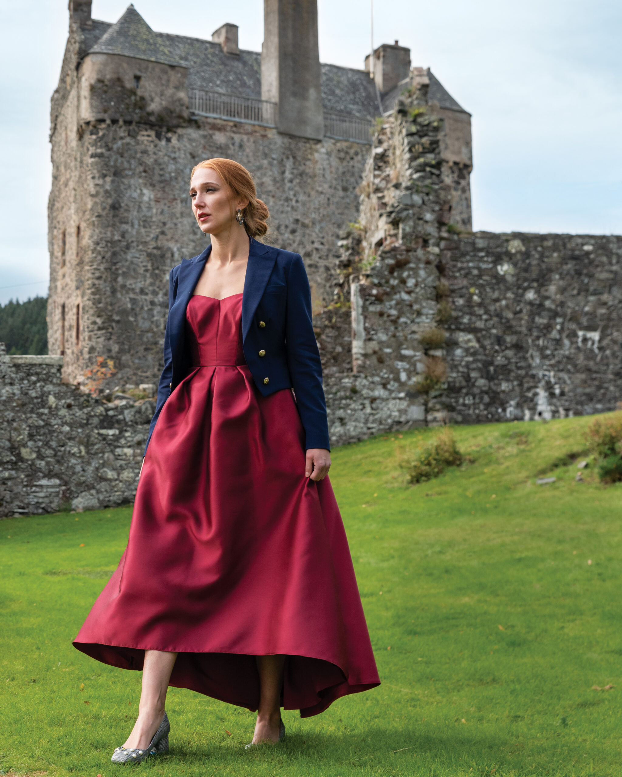 Woman in a red dress standing outside of a castle