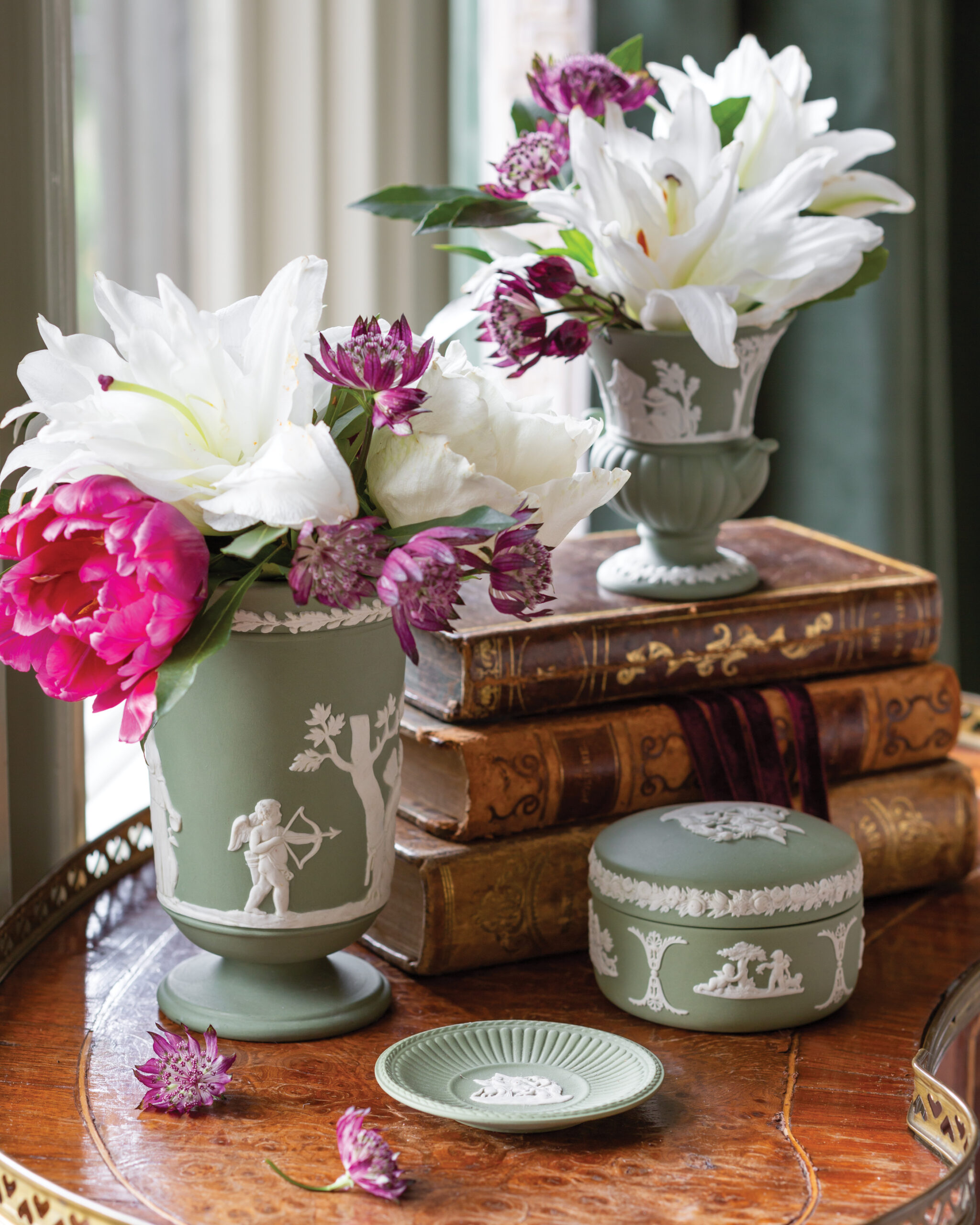 Green vases with florals on top of stacked books