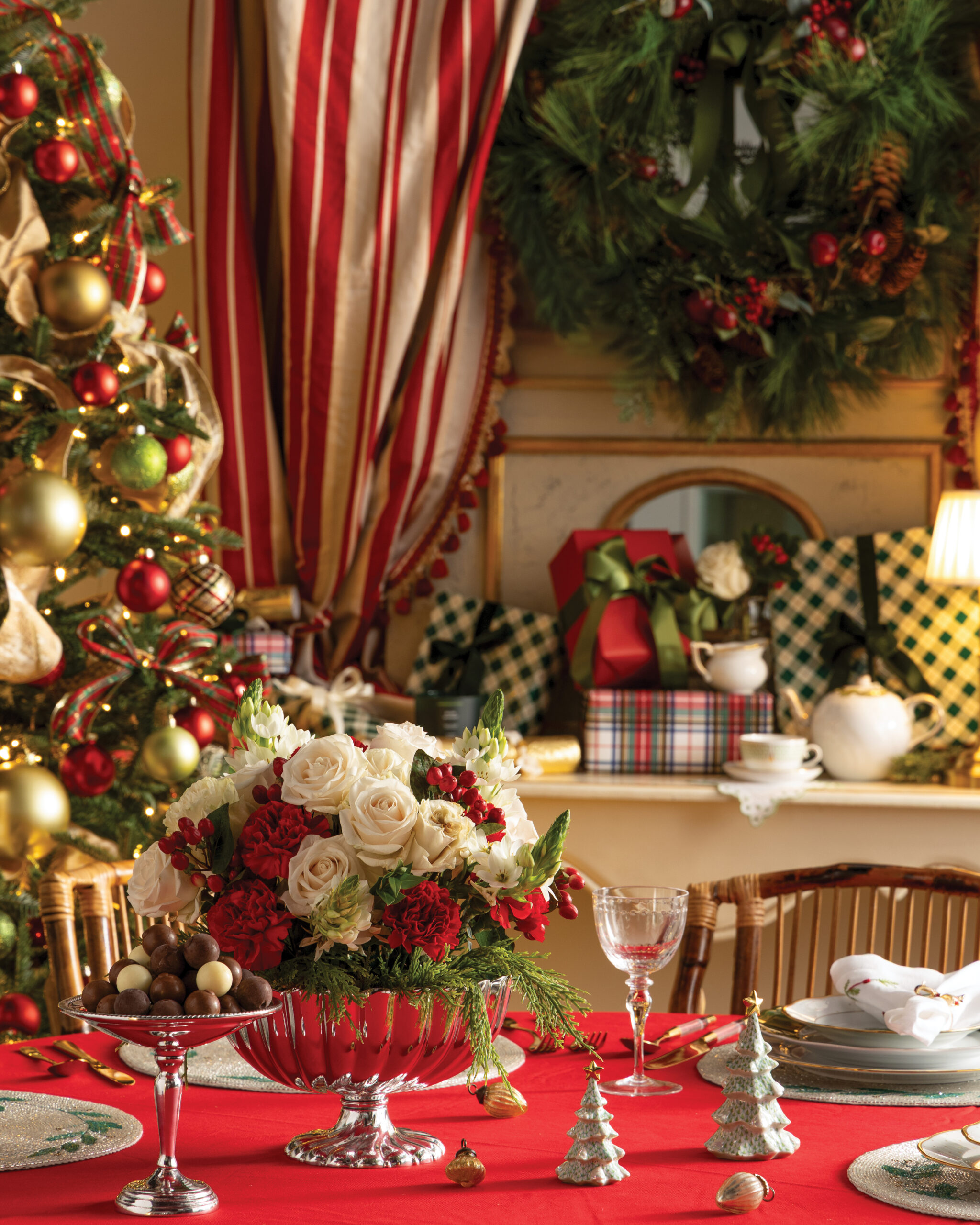 Christmas florals on table with Christmas tree and wrapped presents in the background