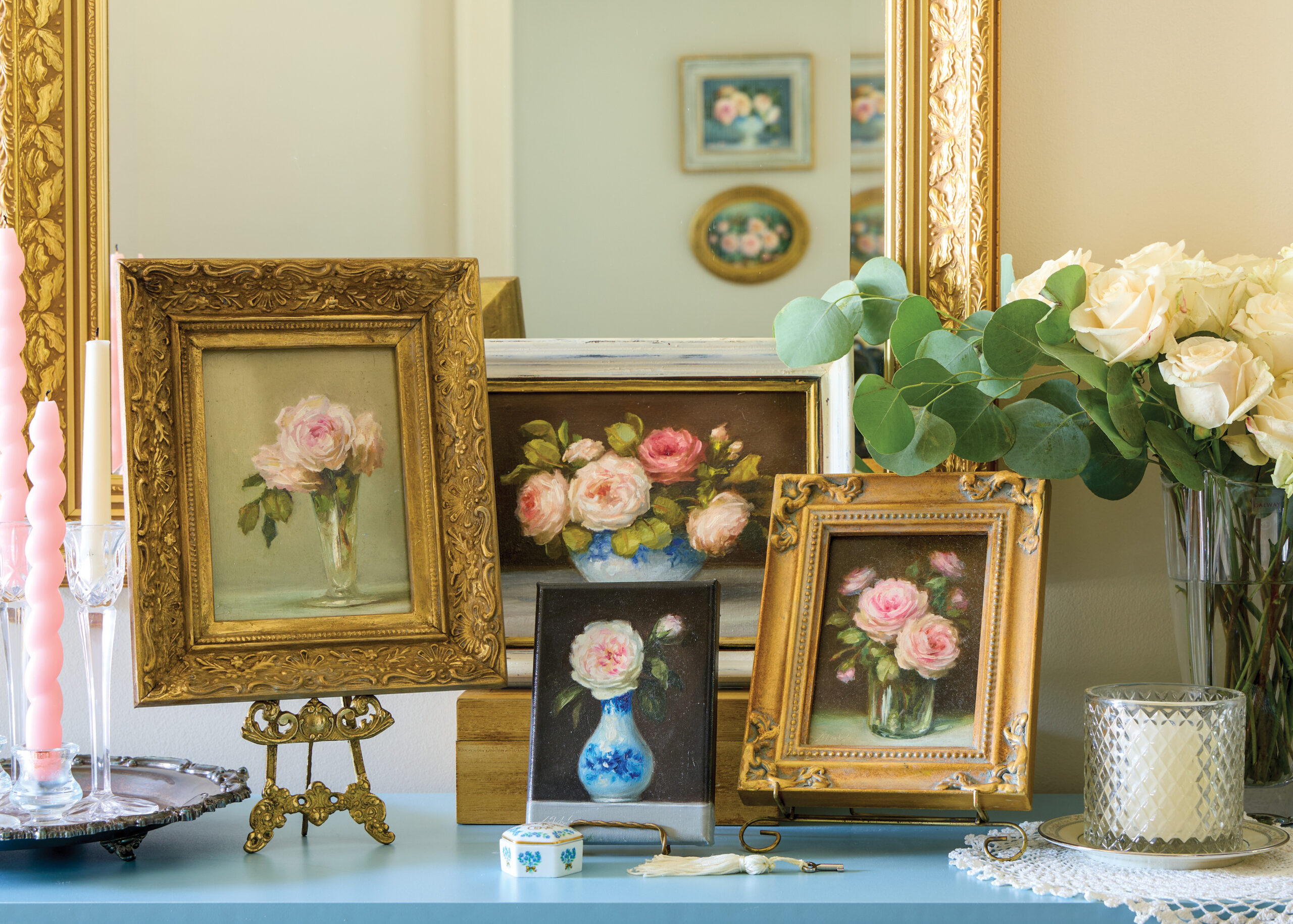 Rose paintings in gold frames displayed on a blue counter