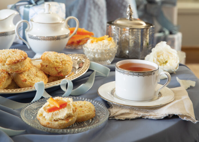 Citrus scones topped with clotted cream next to teacup
