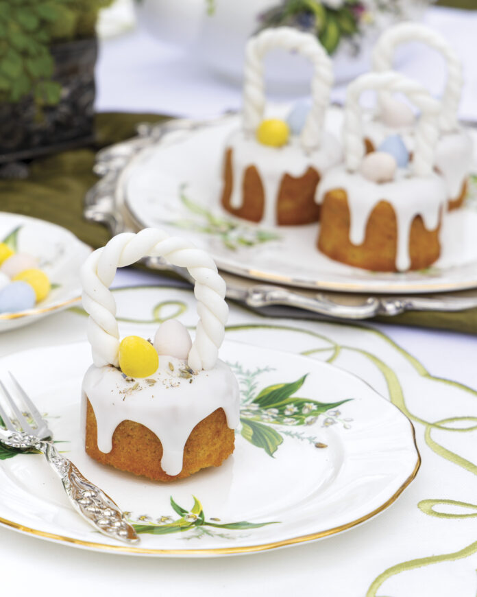 Lavender-Vanilla Mini Cakes, take on the appearance of baskets with fondant handles and toppings of lemon glaze, colorful candy eggs, and culinary lavender.