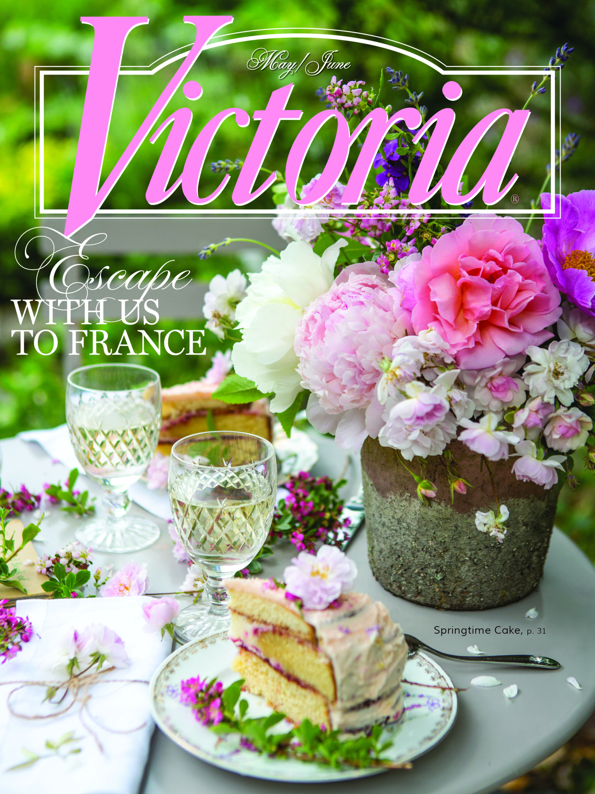 Magazine cover featuring a romantic spring tablescape with lush pink and white peonies arranged in a rustic pot, crystal stemware, and slices of layered cake, overlaid with the title “Victoria” and the line “Escape with Us to France.”