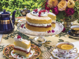 colorful tea service with cake with jam and cream filling cut with one slice